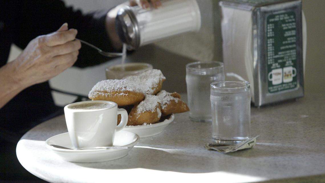 A Cafe Du Monde patron pours sugar into a cup of Cafe Au Lait on opening day at Cafe Du Monde in New Orleans, Louisiana.