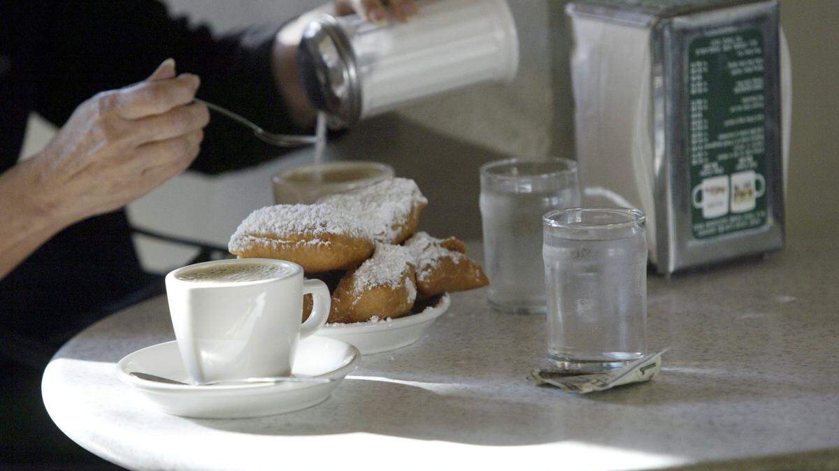 A Cafe Du Monde patron pours sugar into a cup of Cafe Au Lait on opening day at Cafe Du Monde in New Orleans, Louisiana.