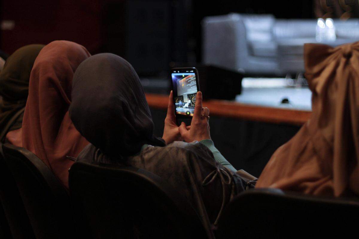 A woman takes a video of part of a panel discussion on Islam, hope and mental health.