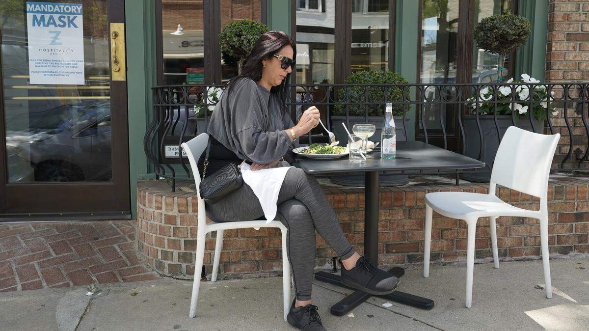 A woman eats lunch alone at an outdoor table.