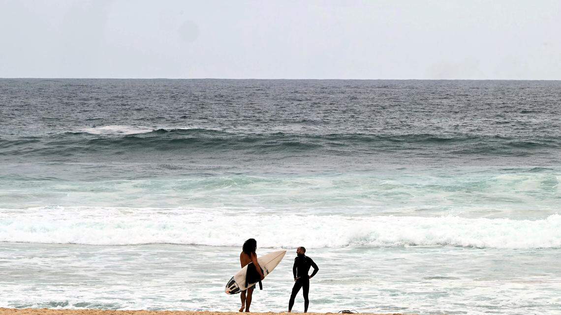 Surfers stand on the sand at Bondi Beach, in Sydney, Australia.
