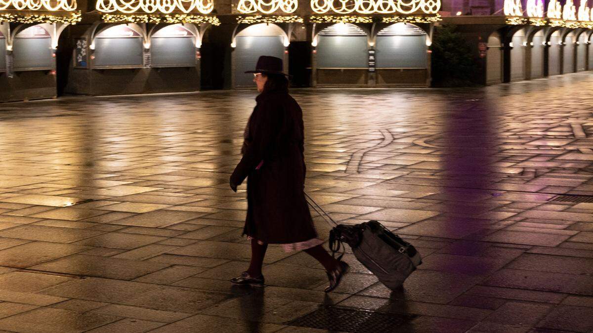 A woman pulling a suitcase walks past a Christmas market next to Stephen’s Cathedral in Vienna, Austria.